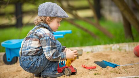 Kleines Kind spielt im Sandkasten.