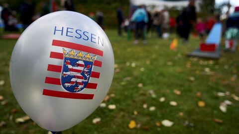 Ein Luftballon mit Hessenwappen vor einer Wiese.