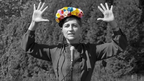 Ulrike Almut Sandig steht vor einem Mikrofon, beide Händen nach oben gestreckt