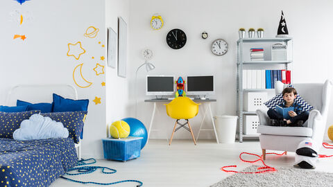 Junge sitzt in sienem Zimmer und liest. Es gibt überall dezente Weltraumdeko.