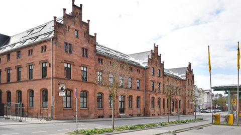 Die Alte Post mit Telegraphenamt in Gießen von außen: Ein großer, langgezogener rötlicher Bau mit schmuckvollen Giebeln