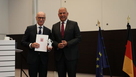 Zwei Männer stehen nebeneinander in einem Raum.