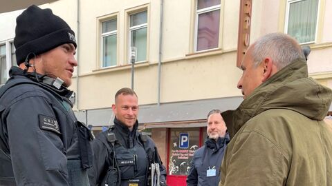Zwei Polizeibeamte und ein Mann stehen auf der Straße.